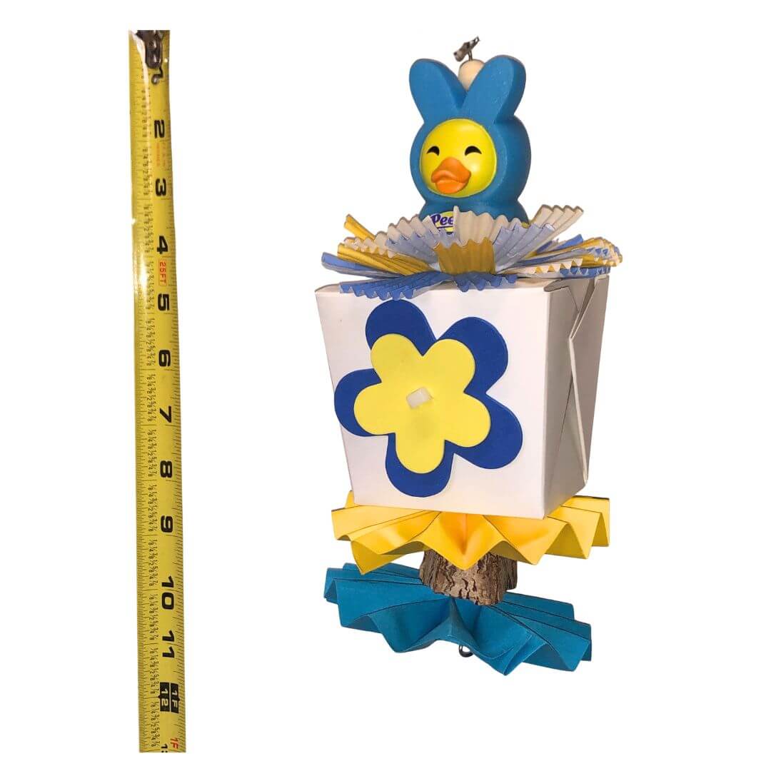 Rubber duck on top of a chinese take out box for foraging. With flowers and pinwheels for spring bird toy