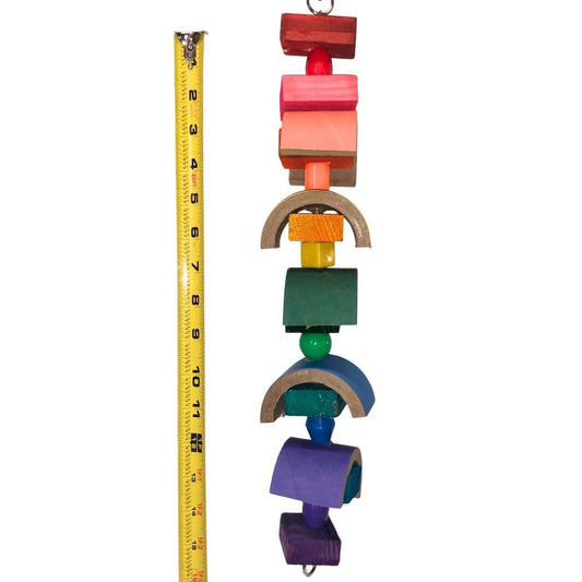 Colorful bird toy with various shapes and a measuring tape for scale on a white background